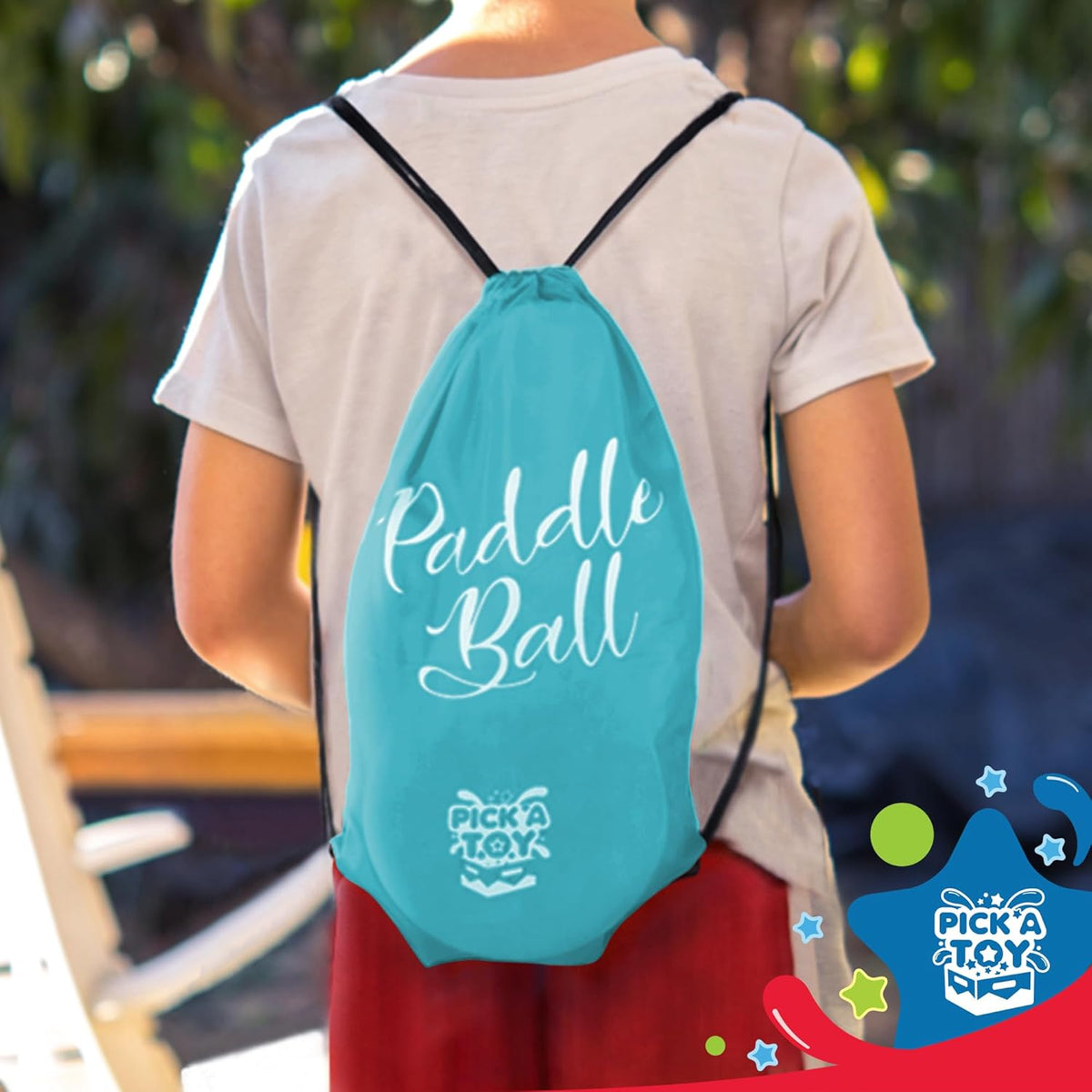 Child outdoors wearing the light blue paddle ball carry bag as a drawstring backpack
