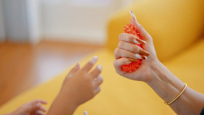 Video showing hedgehog spiky sensory rings in blue, green and orange, and a girl playing with them at a desk